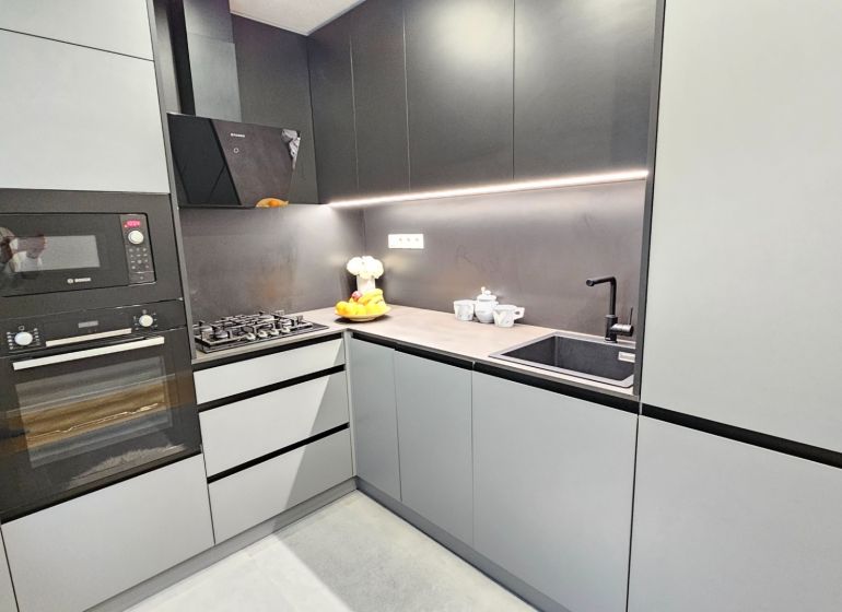 A kitchen in a 2-room apartment with modern appliances and sleek cabinets.