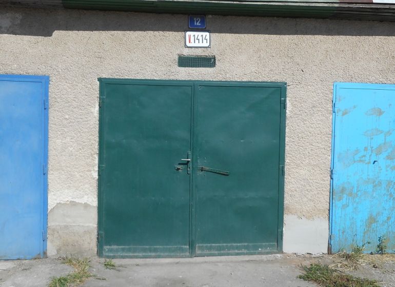 Garages on Ľudovíta Stárka Street in Trenčín with colorful doors and a cement surface.