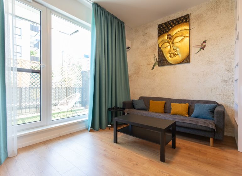 1-bedroom apartment with a wooden decor floor, a sofa, and a Buddha painting on the wall.