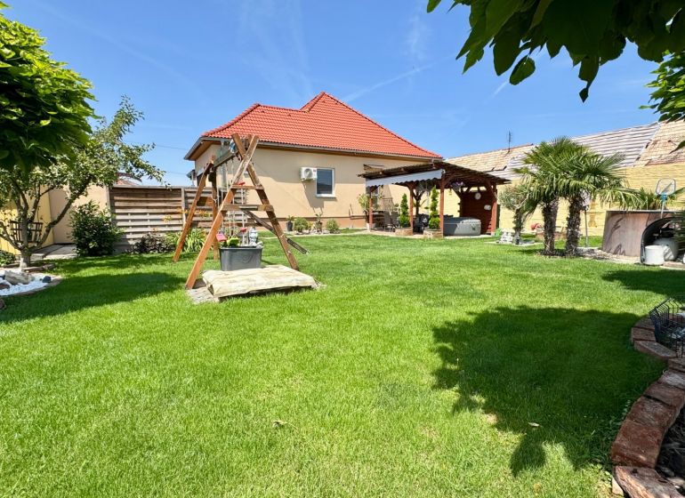 The garden of a family house in Čakajovce with a lawn, a gazebo, and a children's playground.