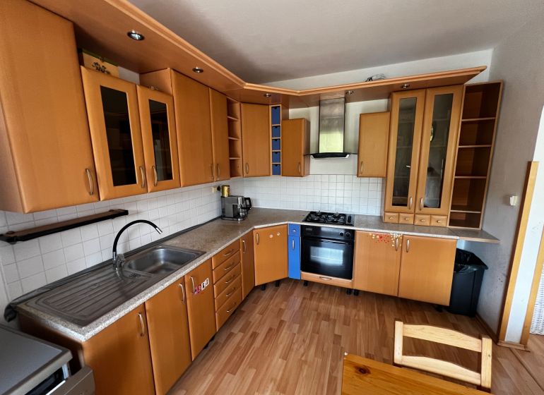 A kitchen in a 3-room apartment with a wood-patterned floor and built-in appliances.