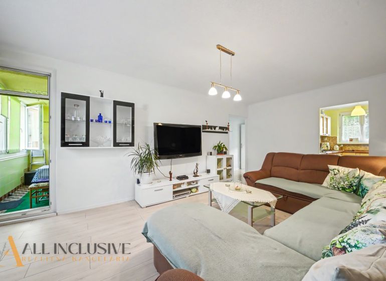 Living room in a 3-room apartment with a large sofa and a television on the wall.