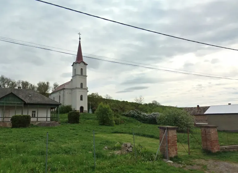 The church with a bell tower in Barca, surrounded by greenery and peculiar properties.
