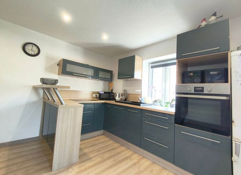 A kitchen in a family house with dark cabinets and a wood-patterned floor.