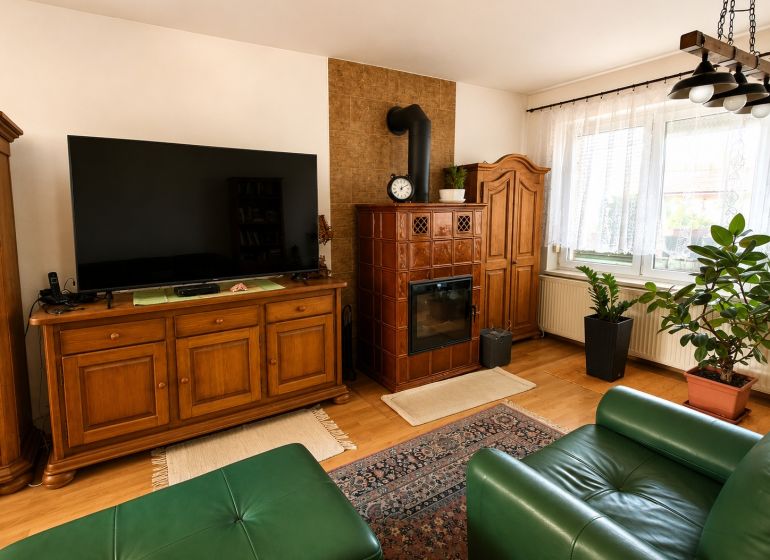 Living room in a family house with a tiled stove, television, and wooden decor.