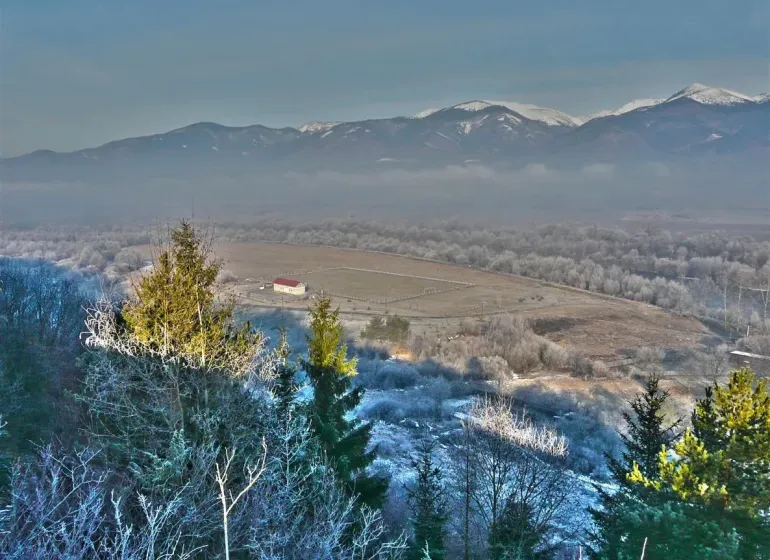 Winter landscape around Nolčovo with snow-covered agricultural and forest lands and mountains in the background.
