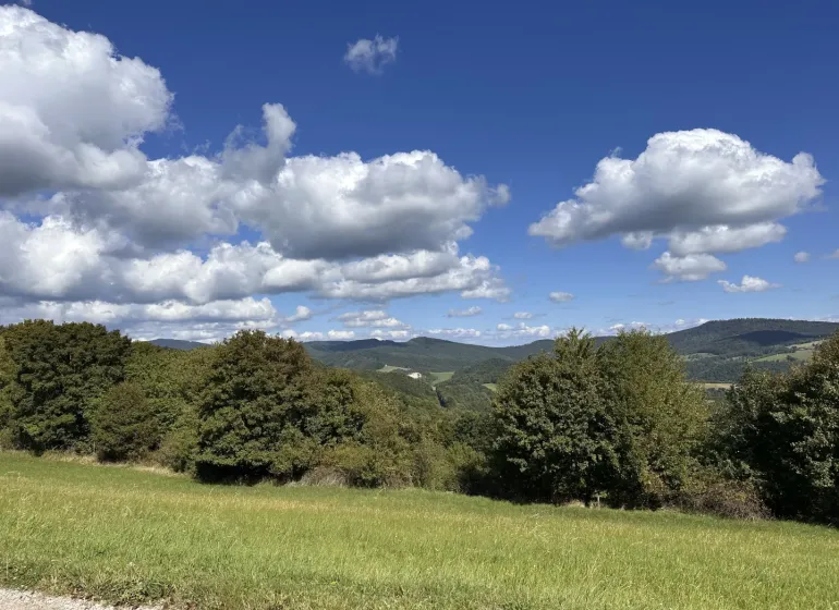 Landscape in Hankovce with agricultural and forest lands, blue sky, clouds.