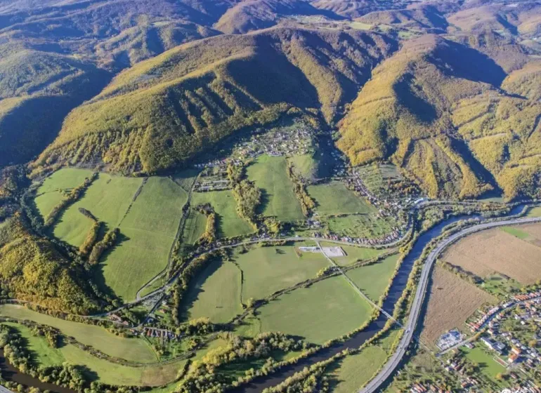 Aerial view of agricultural and forest land in Orovnica with a river and a highway.
