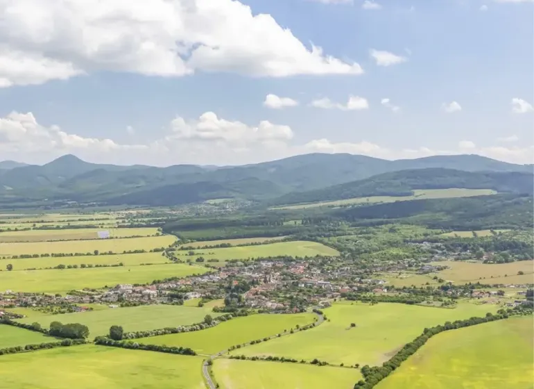A view of agricultural and forest lands around Jablonové with mountains in the background.