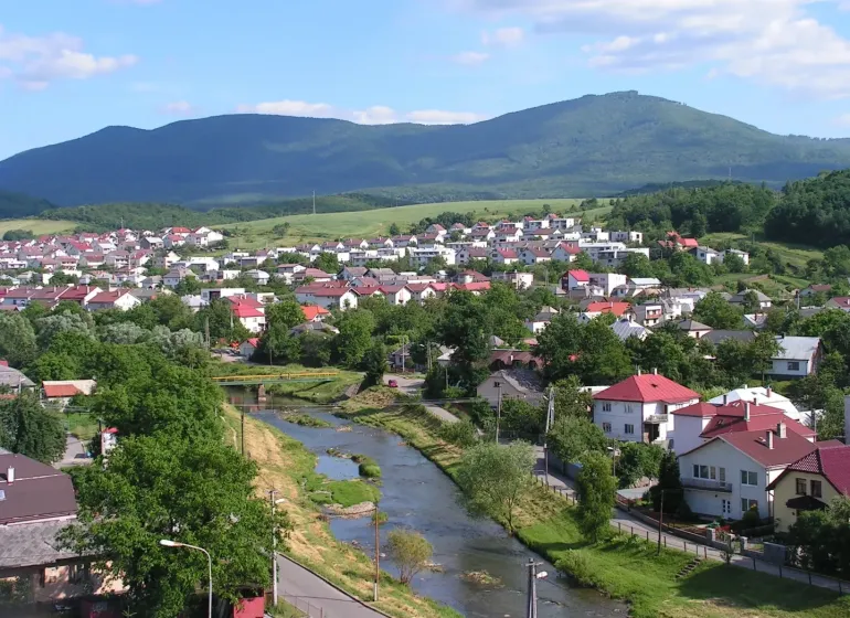 Panorama of Snina with a river, houses, and hills in the area of Special Properties.