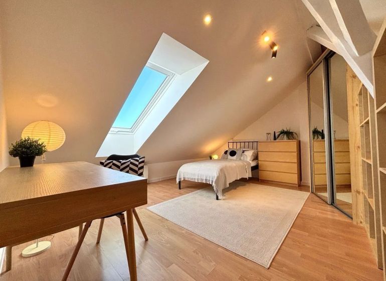 Attic room with a table, bed, and mirrored wardrobe in a 4-room apartment.