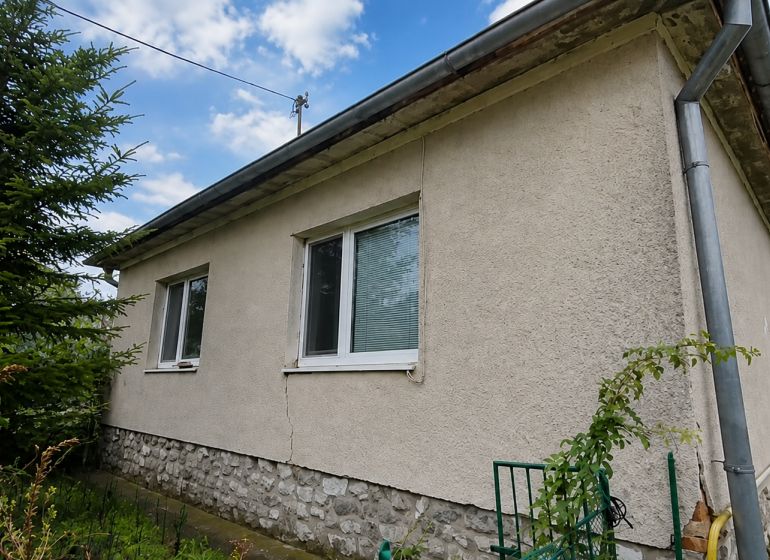 A family house in Veľké Ripňany with a gray facade and a stone plinth.