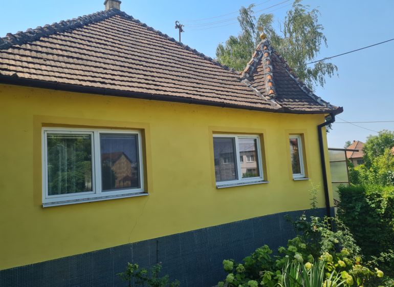 A family house in Komjatice with a flower garden and a yellow facade.