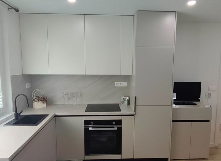 A kitchen in a 3-room apartment with a wooden decor floor and modern cabinets.