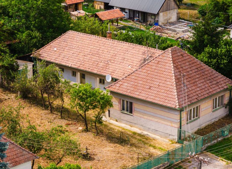 A family house in Kapince with a large garden, surrounded by green trees.