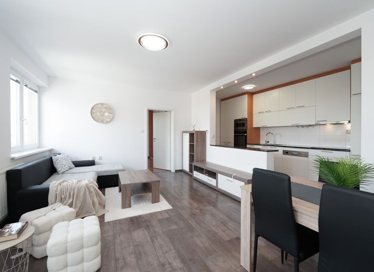 Living room with kitchen in a 3-room apartment with a wooden decor floor.
