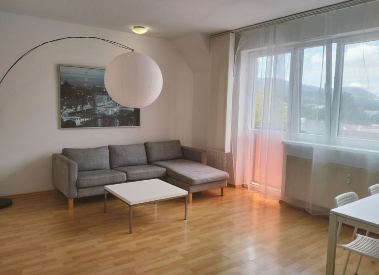 Bright living room in a 2-room apartment, sofa, table, wooden decor flooring.