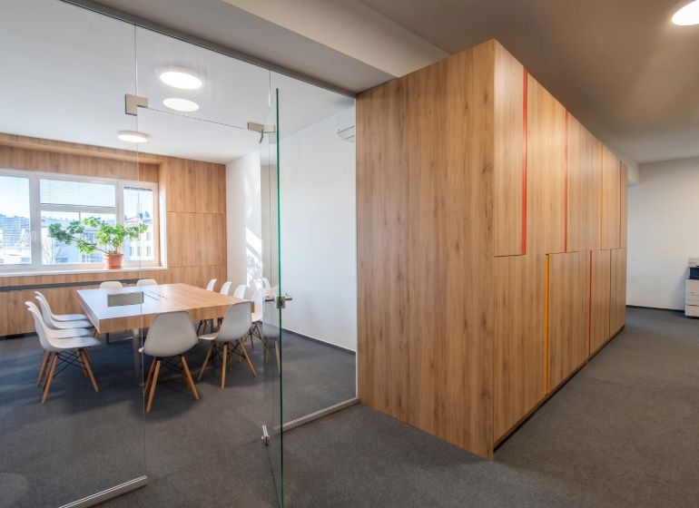Offices with wood-patterned flooring and glass doors, furnished with chairs and a table.