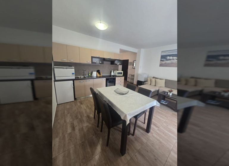 The kitchen of a two-room apartment with a corner sofa and a floor with a wooden decor.