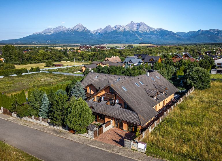 A family house in Veľká Lomnica, surrounded by mountains, in the middle of a green landscape.
