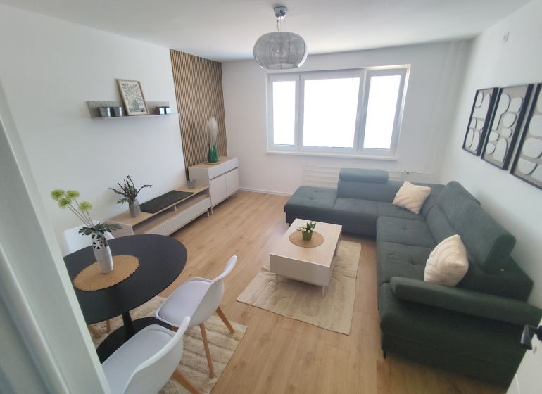 Living room in a three-room apartment with a wooden decor floor and a comfortable sofa.