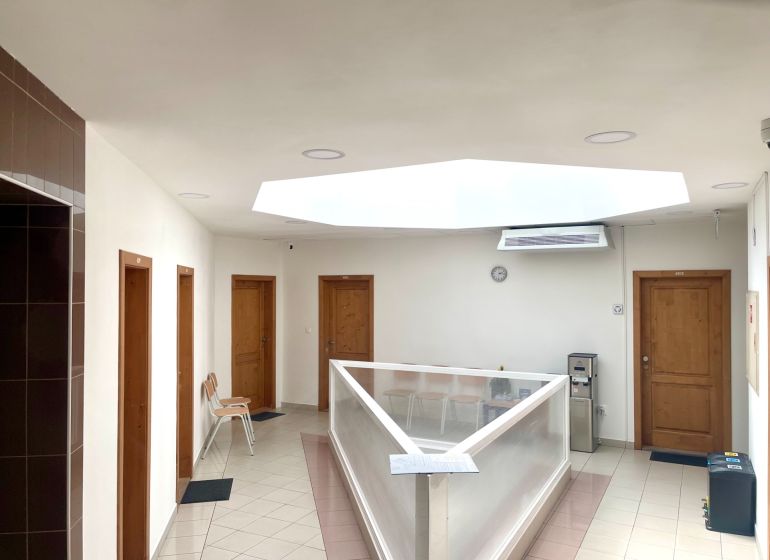 Hallway in the office with doors, skylight, chairs, and a water dispenser.