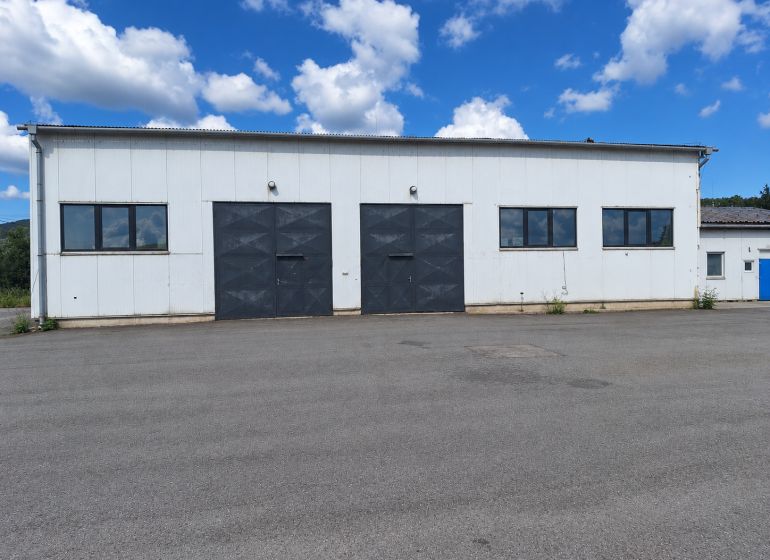 Warehouse and hall building in the village of Ličartovce, with large gates and an asphalt surface.