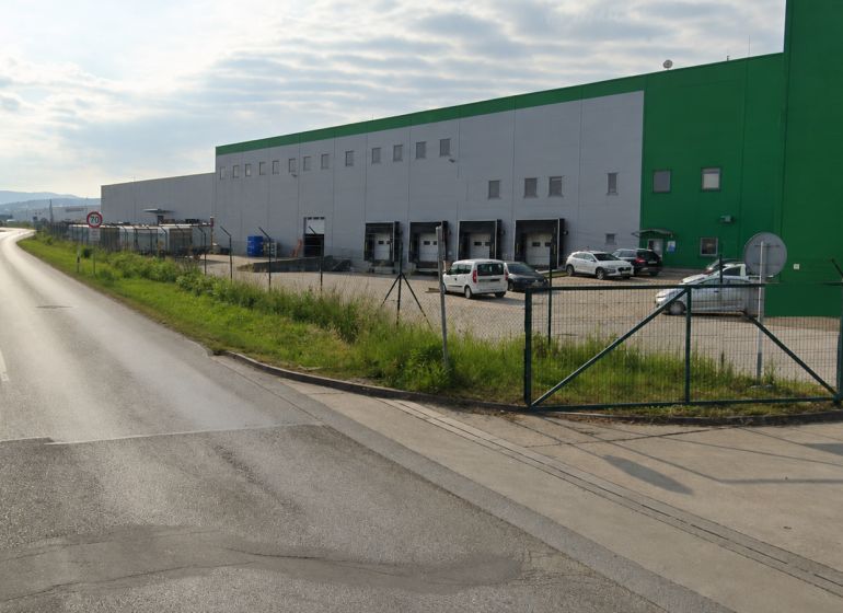 Warehouses and halls in the Záborské district in Prešov by the road with vehicles.