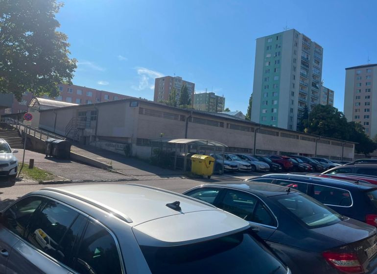 Parking lot near garages in Bratislava - Karlova Ves, Púpavová, surrounded by tall buildings.