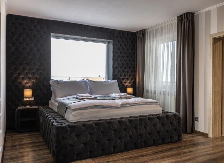 Bedroom in a 2-room apartment with a bed and a wooden decor floor.