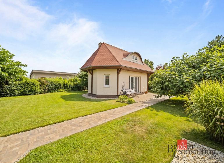 A cottage in Vojka nad Dunajom surrounded by a lawn and trees with a stone pathway.