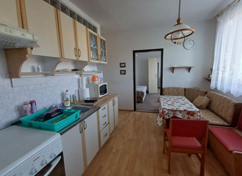 A kitchen in a 3-room apartment with a wooden decor floor and a corner sofa.