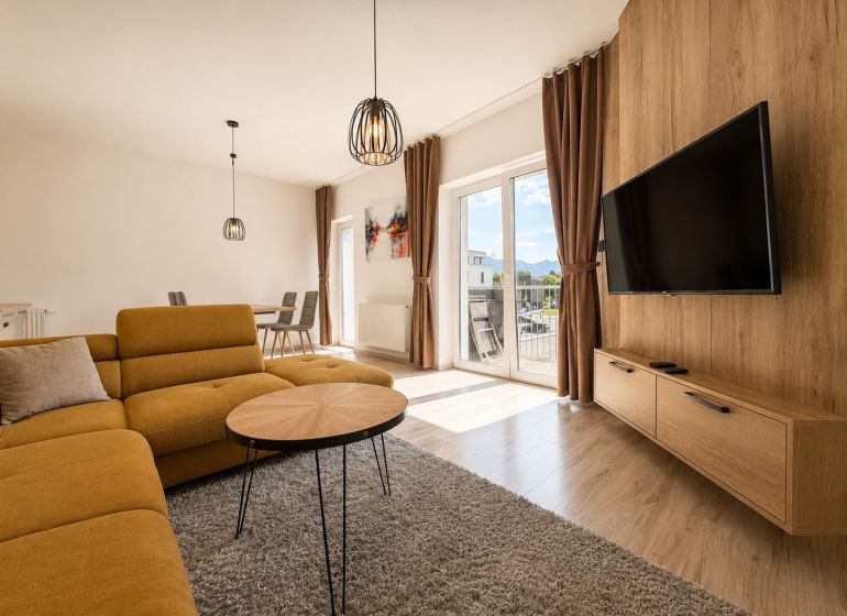 Living room in a 3-room apartment with a sofa, table, TV, and floor with a wooden decor.
