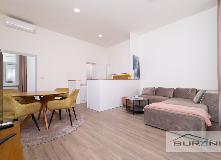 Living room in a two-room apartment with a wooden decor floor, yellow chairs, sofa.