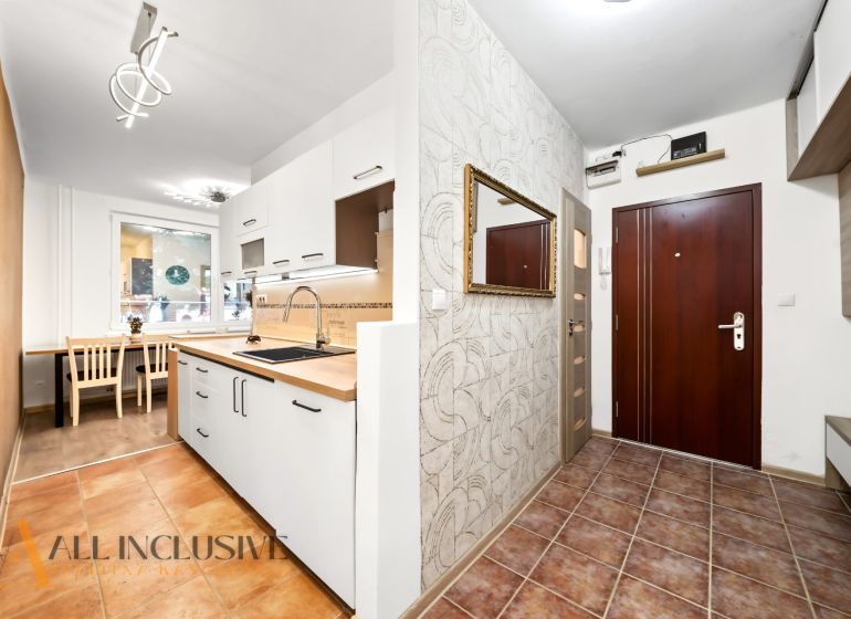 A kitchen in a 2-room apartment with white cabinets and tiled flooring.