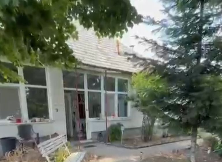 A family house in Imel with a bench, trees, and a garden path.