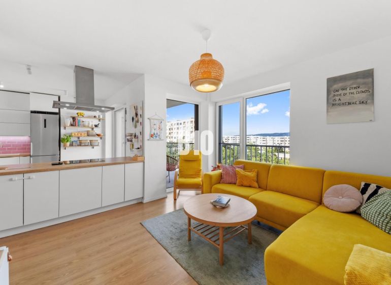 Living room of a 4-room apartment with a wooden decor floor and a yellow sofa.
