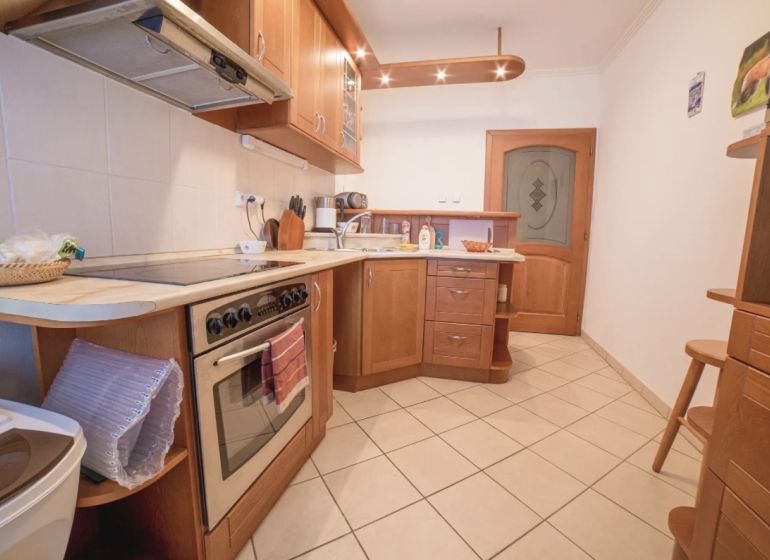 A kitchen in a 3-room apartment with wooden cabinets and ceramic flooring.