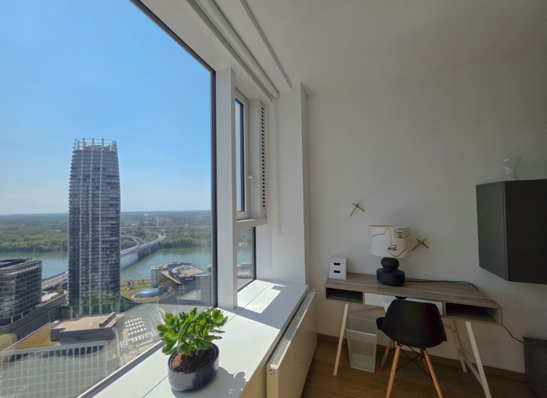 Interior of a 1-bedroom apartment with a view of the river and modern architecture.