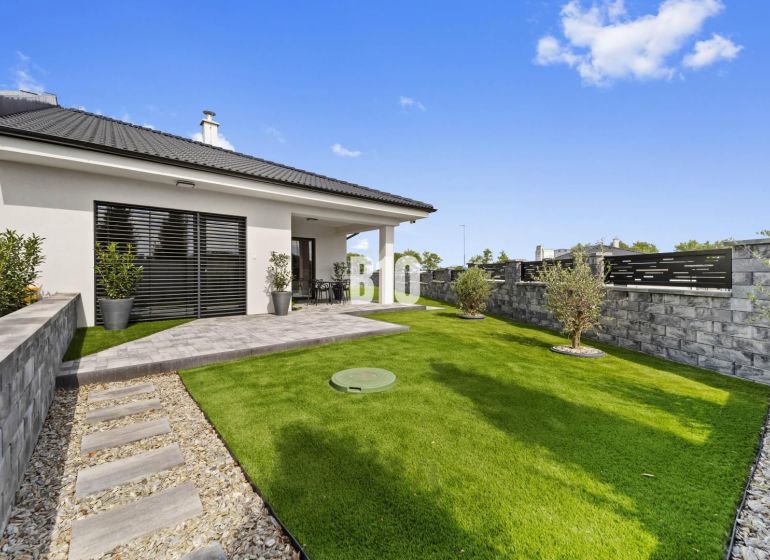 A family house in Nitra with a garden, lawn, and terrace surrounded by a wall.