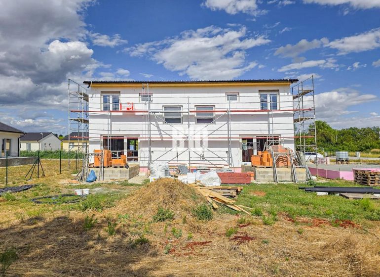Construction of a family house in Nitra with scaffolding under construction and materials on the site.
