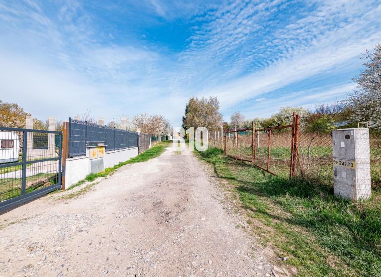 A path between residential plots in Nitra, between fencing and green vegetation.