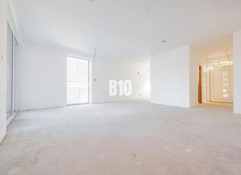 A spacious white interior of a family house with plenty of natural light and balcony doors.