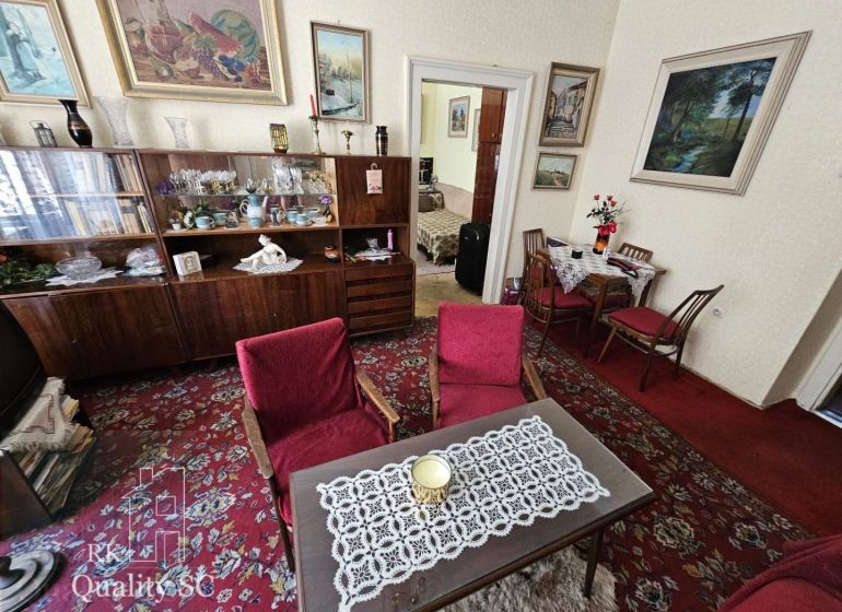 Living room in a two-room apartment with a red carpet and a wooden wall unit.