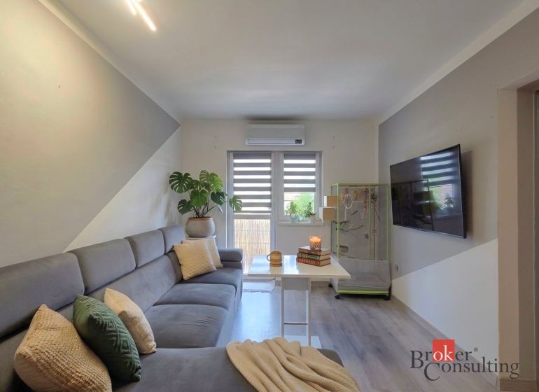 Living room in a 4-room apartment with a comfortable sofa and a TV on the wall.