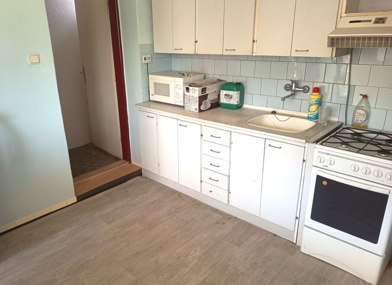 A kitchen with white cabinets, a microwave, and a wooden decor floor in a family house.