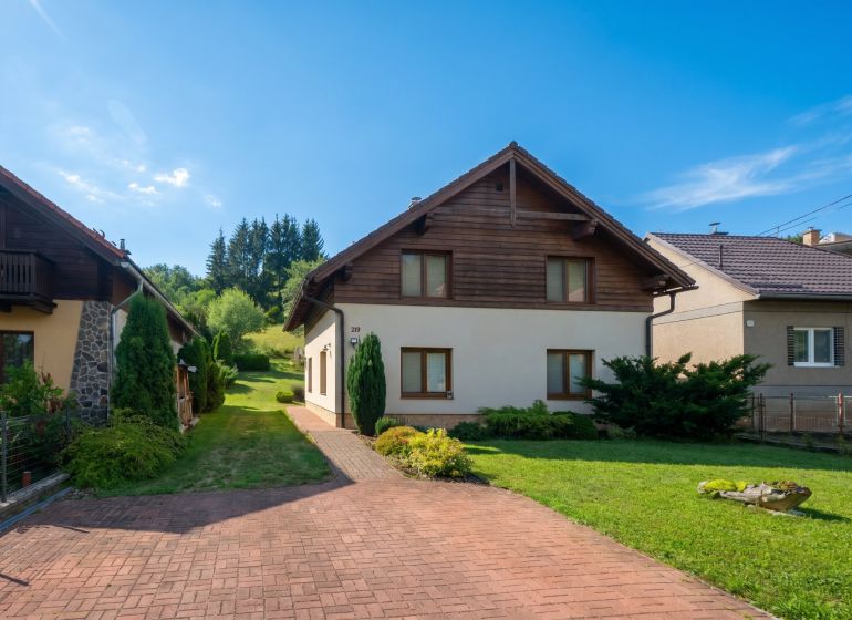 A family house in Horná Lehota surrounded by a garden with a lawn and a driveway.