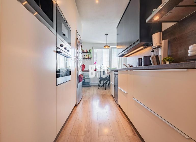 A kitchen in a 3-room apartment with a wooden decor floor and appliances.