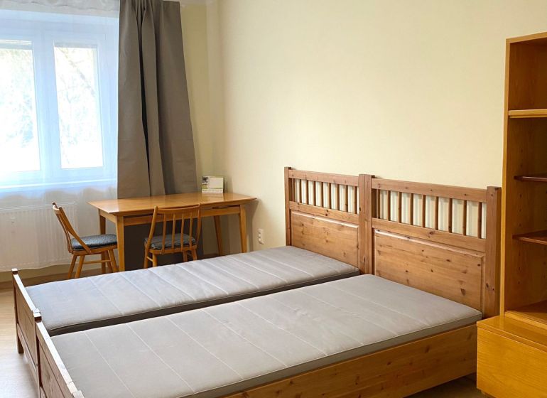 A bedroom with wooden beds, a table, and a floor with a wooden decor in a 3-room apartment.
