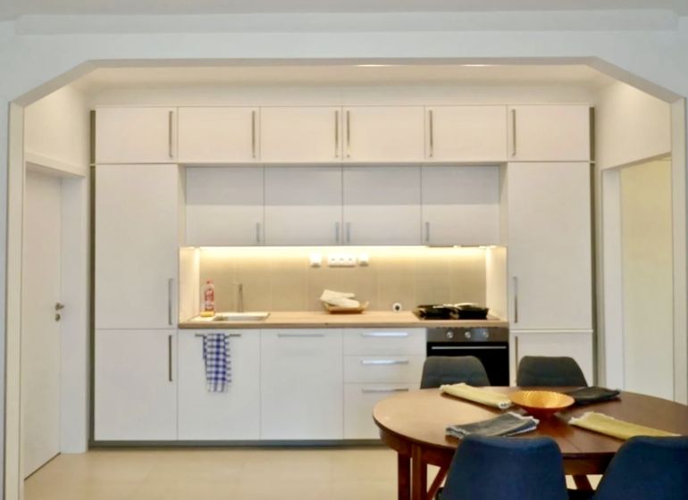 A kitchen in a 3-room apartment with a white kitchen unit and a dining table.